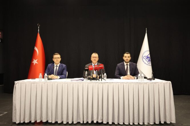 Alt metin: Üç kişi, mikrofonlar ve kamera önünde, basın toplantısı yapıyor.